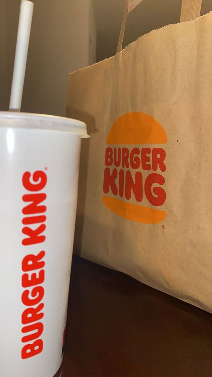 a cup with a straw in it sitting next to a bag that says burger king