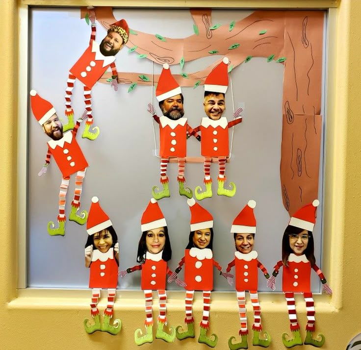 a group of elfs hanging from a tree in front of a bulletin board with pictures on it