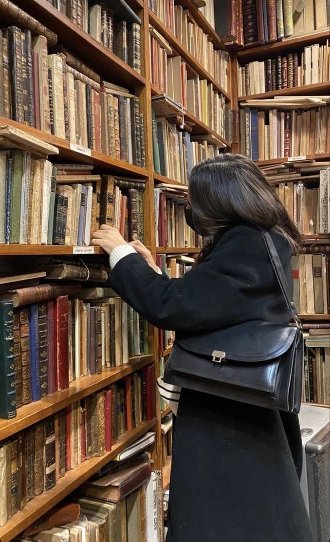 a woman looking at books in a library