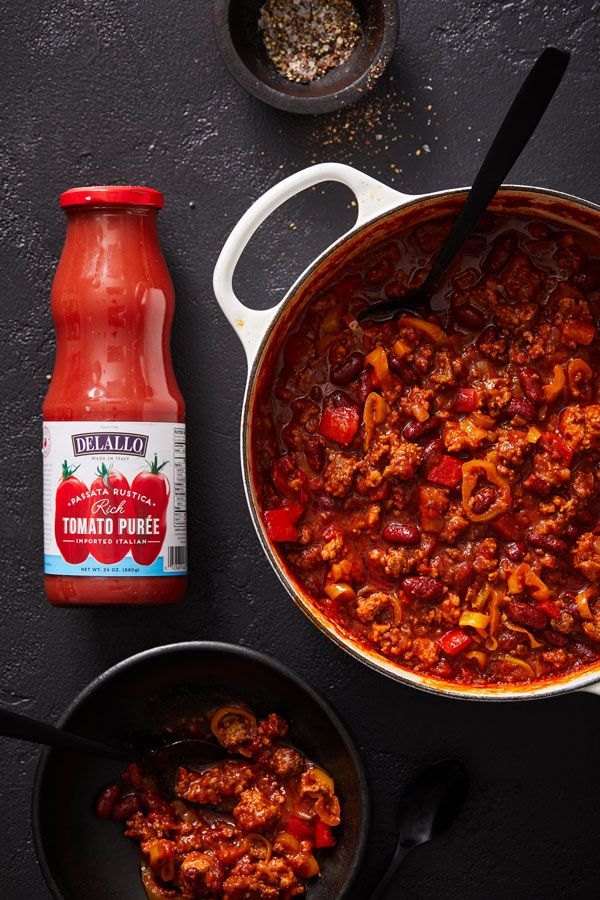 chili sauce in a pot next to a bottle of ketchup on a table