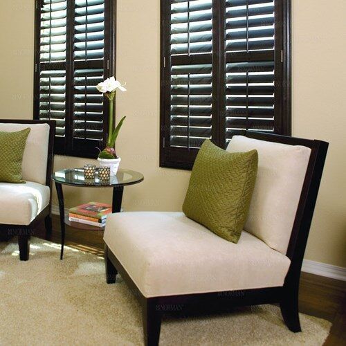 a living room filled with furniture and two windows covered in shutters, sitting next to each other