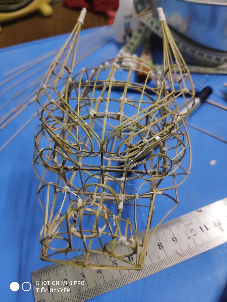 a metal sculpture sitting on top of a blue table next to a ruler and measuring tape