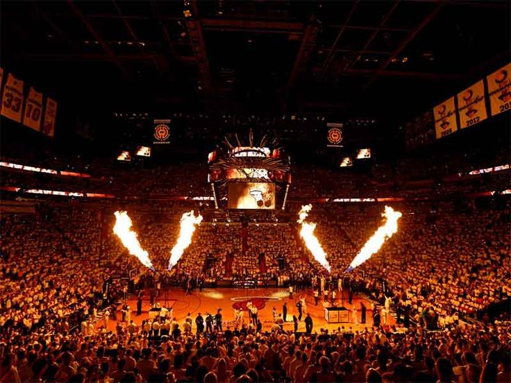 an arena filled with lots of people and flames in front of the crowd at a basketball game