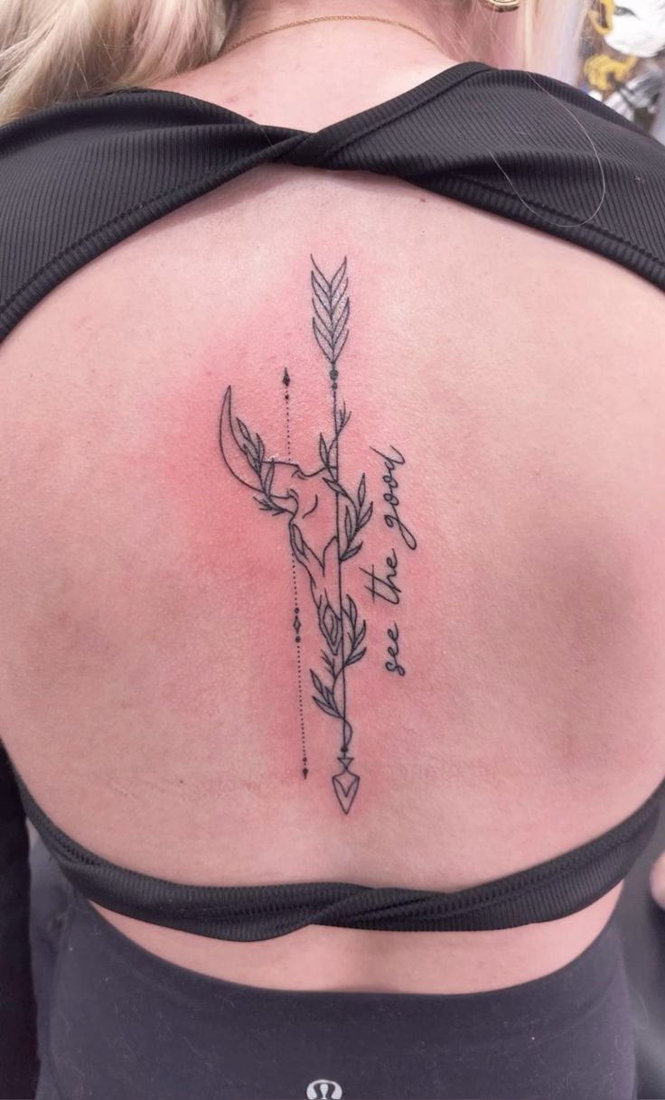 a woman's back with an arrow tattoo on it