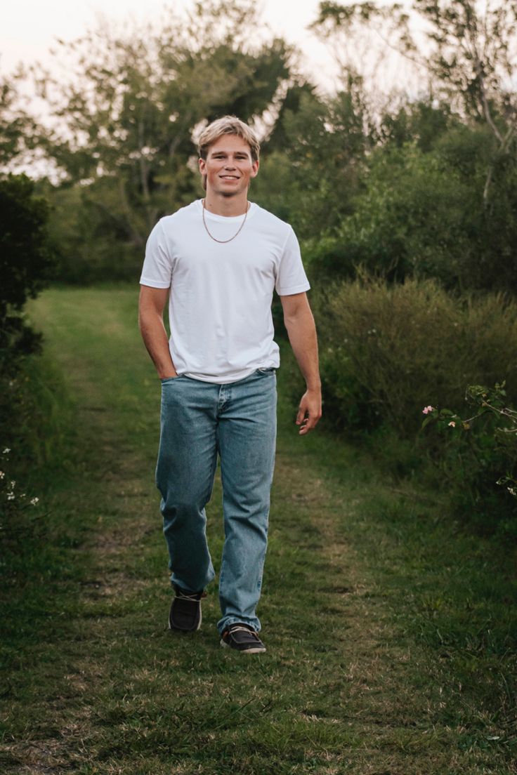 a man standing in the middle of a field wearing jeans and a white t - shirt