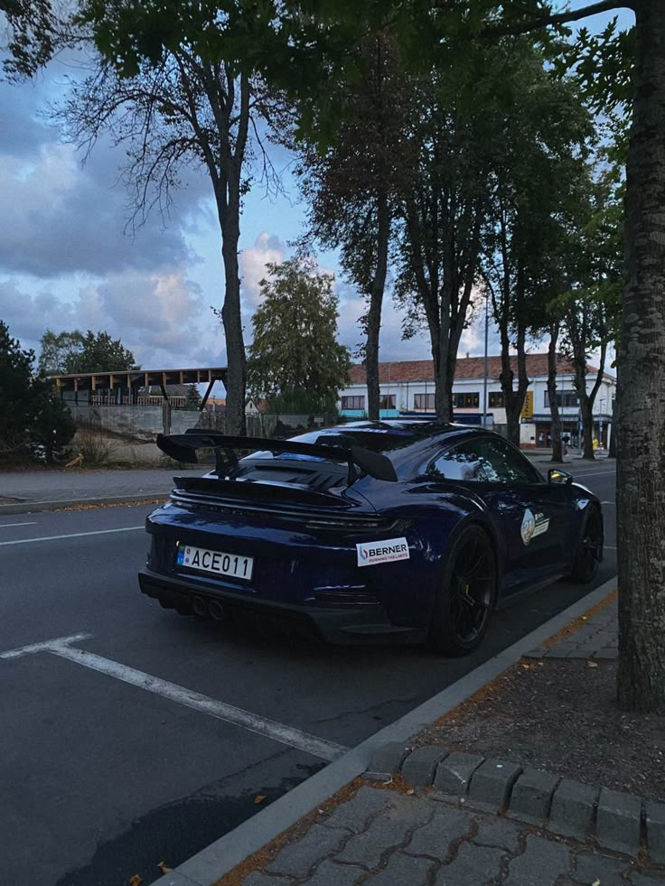 a blue sports car is parked on the side of the road next to some trees