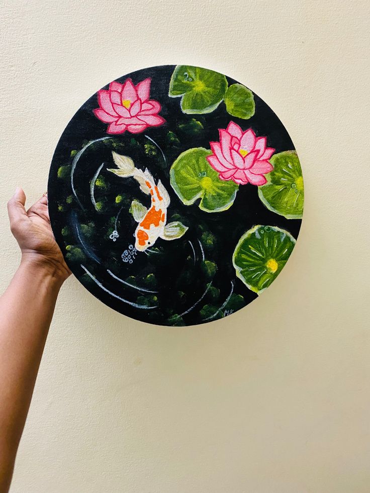 a person holding up a plate with water lilies and koi fish on it