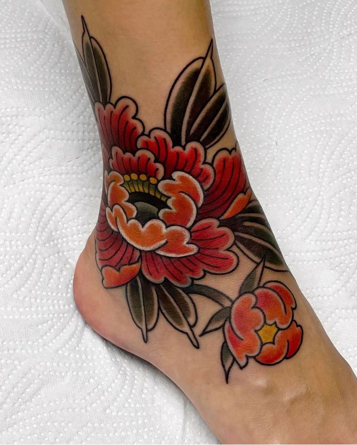 a close up of a person's foot with flowers on it and an orange flower in the center