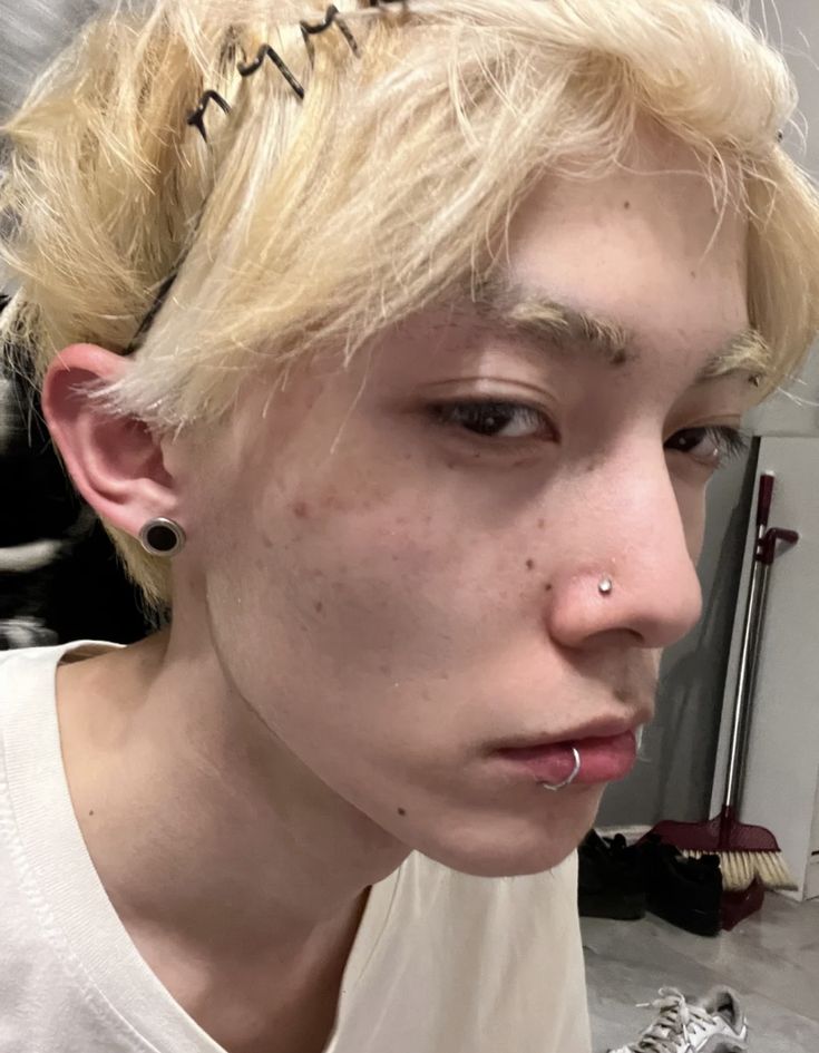 a woman with blonde hair and piercings on her nose is looking at the camera