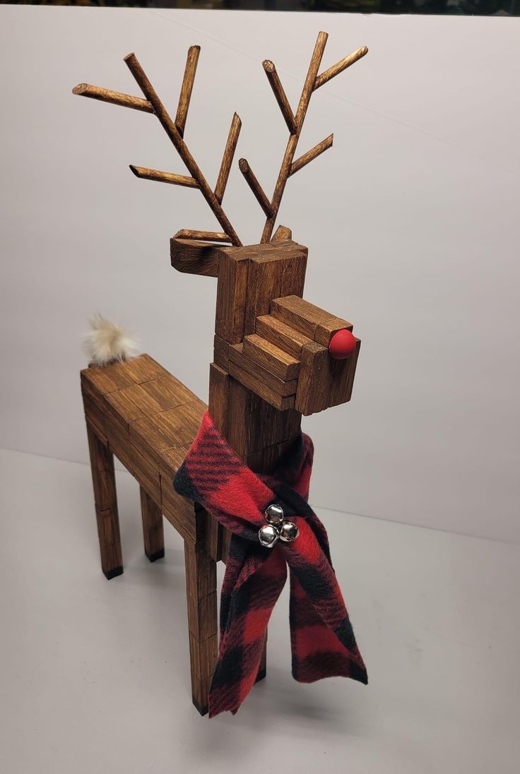 a wooden reindeer sitting on top of a bench next to a red and black scarf