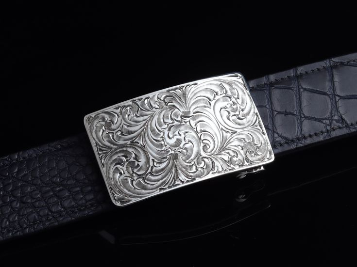 One of our most popular buckles, this understated piece by Comstock Heritage is perfect for those just starting their buckle collections, or for more formal occasions. It’s made from heavy-gauge, hand-engraved Sterling silver, and its rectangular face is adorned with beautiful, delicate scrollwork. This buckle can be paired easily blue jeans or be worn with dressier slacks. Smaller size measures 1 ⅝” x 2 ⅝” and fits all 1 ¼" belt traps Larger version measures 1 ⅞” x 2 ¾" and fits all 1 ½" belt s Classic Polished Belt Buckles For Formal Occasions, Luxury Engraved Silver Belt Buckles, Classic Silver Belt Buckles With Polished Finish, Classic Engraved Belts For Formal Occasions, Classic Formal Belts With Engraved Details, Classic Formal Belt With Engraved Details, Classic Formal Engraved Belt, Elegant Polished Belt Buckles For Formal Occasions, Designer Formal Belt Buckle Rectangular