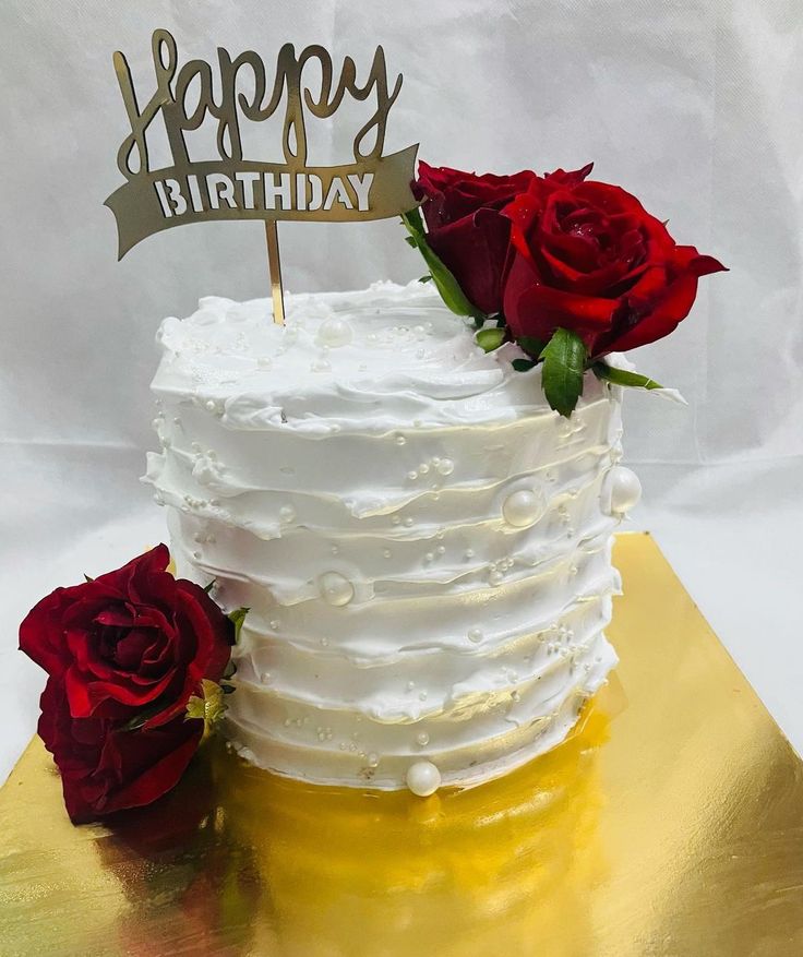 a white cake with red roses and a happy birthday sign