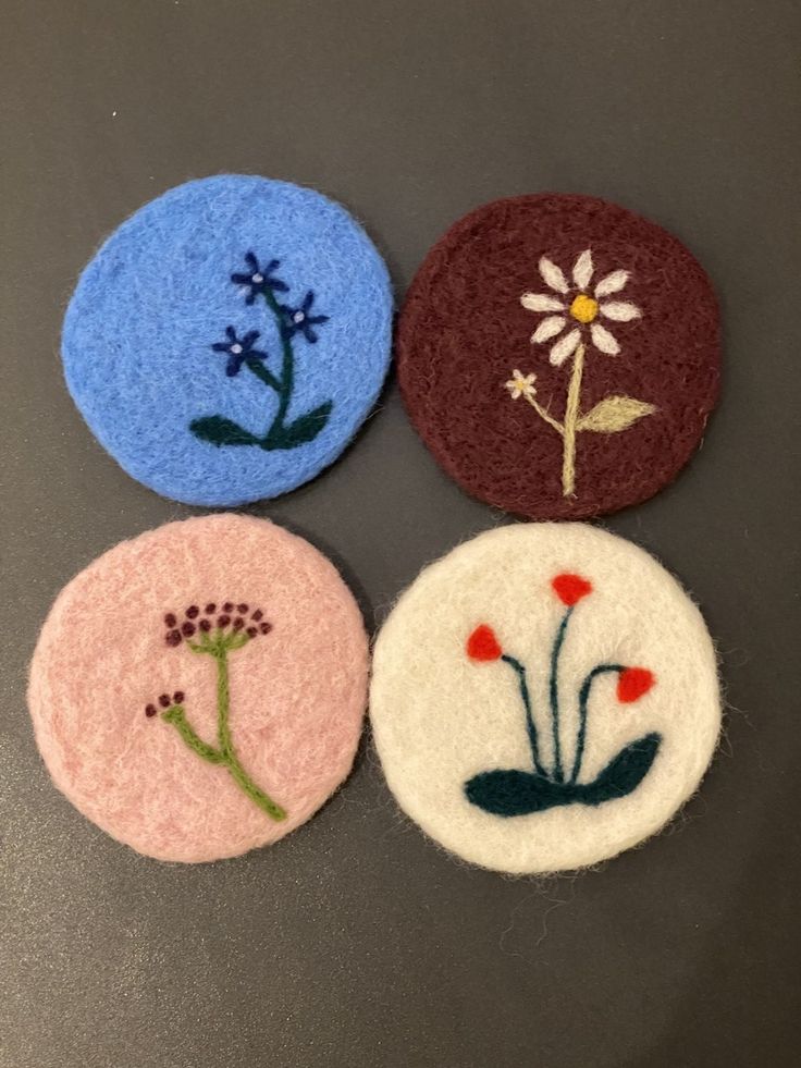 four different colored buttons with flowers on them sitting on a counter top next to each other