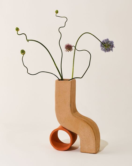 a wooden vase with flowers in it sitting on a table next to a white wall