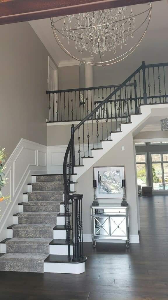 a staircase with chandelier and white walls