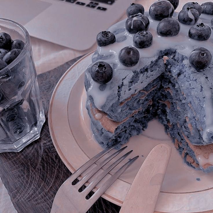 a blueberry cake on a plate with a knife and fork next to the cake