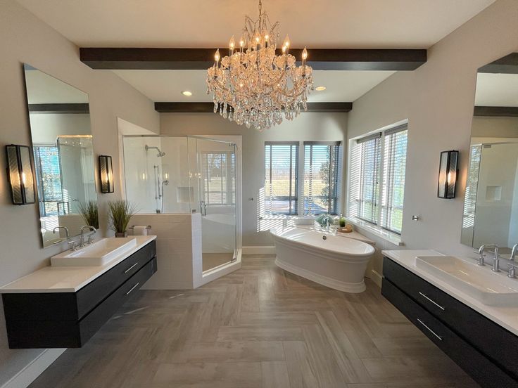 a large bathroom with two sinks, tub and chandelier in the middle of it