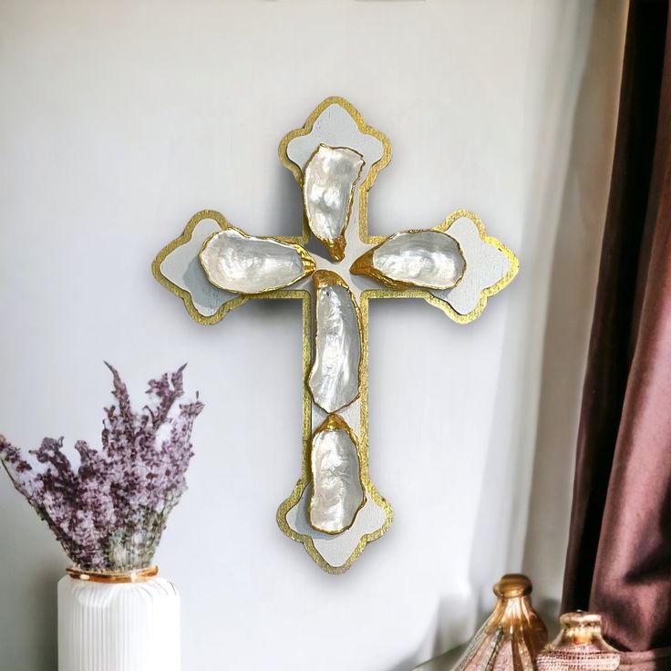 a cross is mounted on the wall next to a vase with lavenders in it