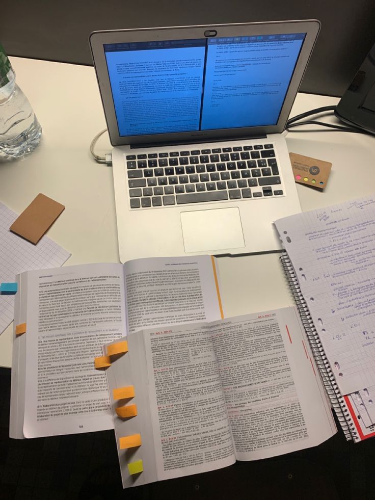 an open laptop computer sitting on top of a white desk next to papers and pencils