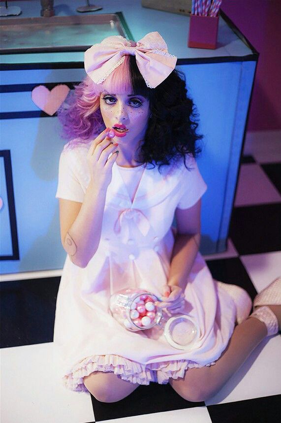 a woman sitting on top of a table with candy in her hand and wearing a pink bow