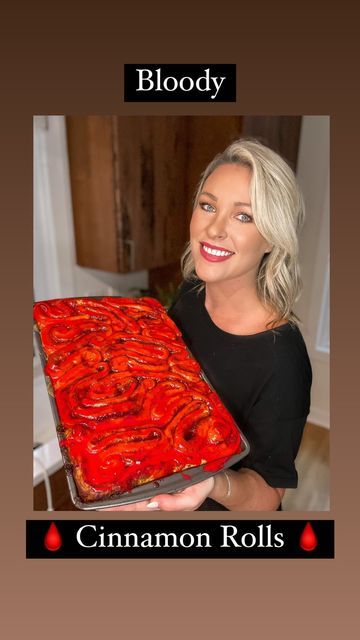 a woman holding a large red cake in front of her face with blood and cinnamon rolls on it