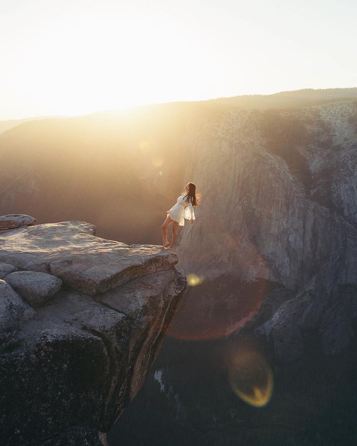 a woman standing on the edge of a cliff