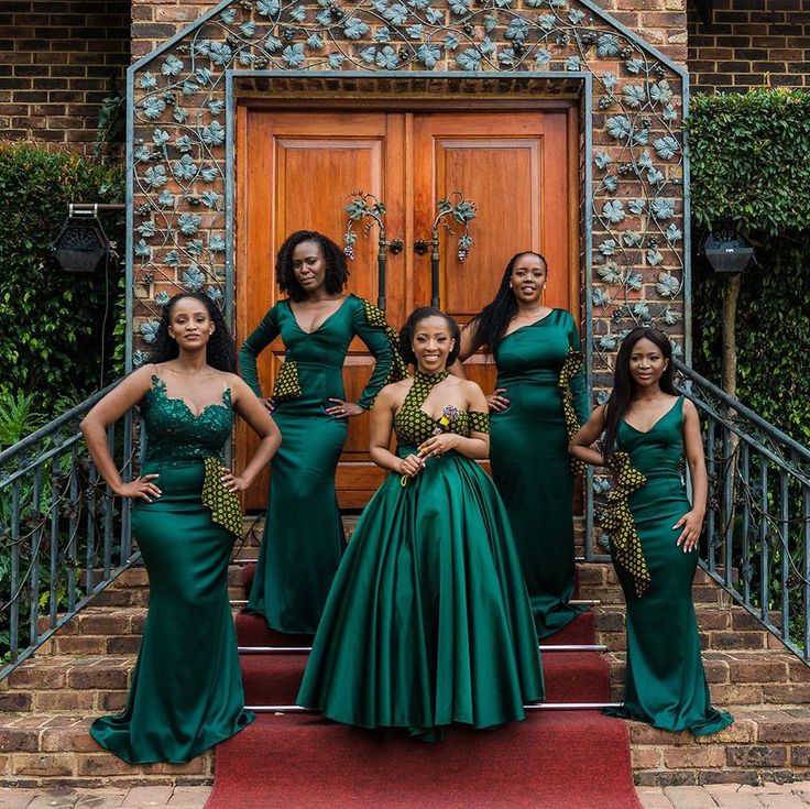 a group of women standing next to each other in front of a door wearing green dresses