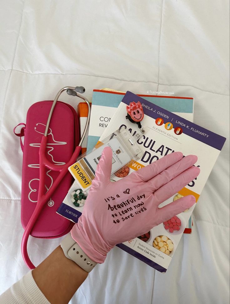 a person's hand in pink gloves next to books and a stethoscope