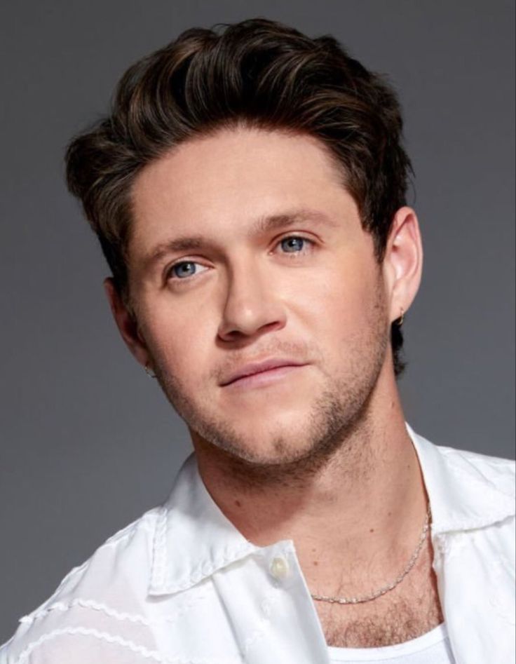 a close up of a person wearing a white shirt and looking at the camera with a serious look on his face