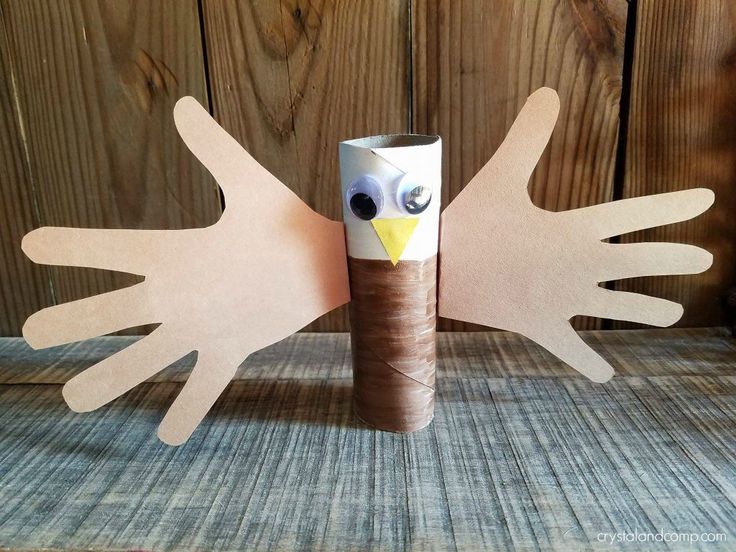 a bird made out of toilet paper on top of a wooden table next to a roll of tape