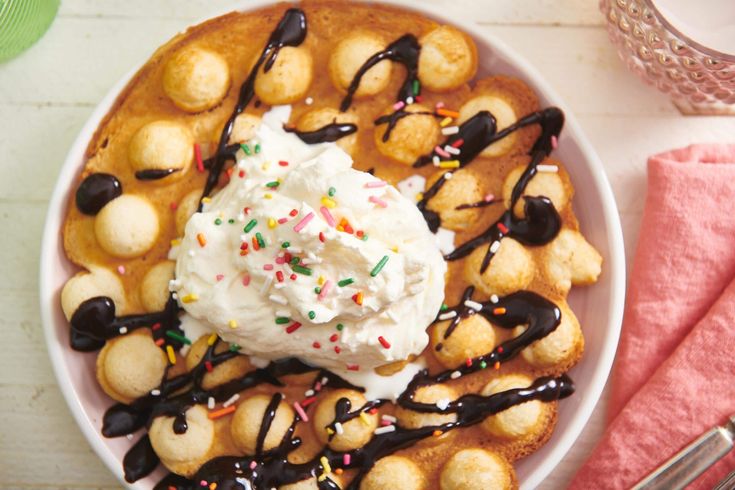 a white plate topped with waffles covered in whipped cream and sprinkles