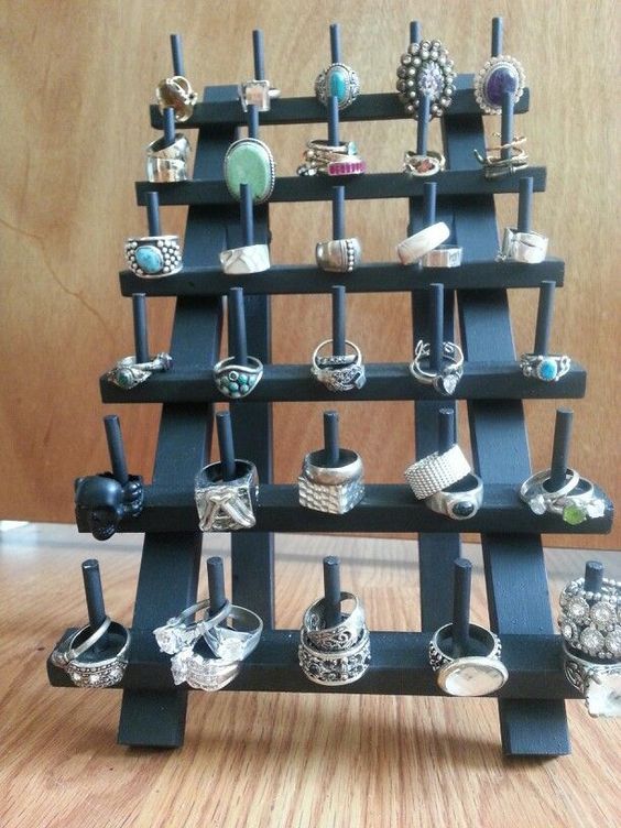 a display case with rings and bracelets on the bottom shelf in front of a wooden wall