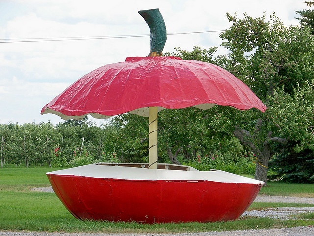 a large red boat sitting on top of a lush green field