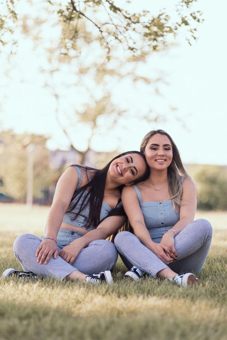 two young women sitting on the ground hugging each other