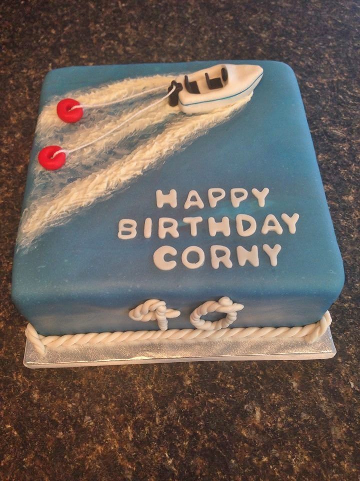 a blue birthday cake with a boat on it and the words happy birthday corny written in white frosting