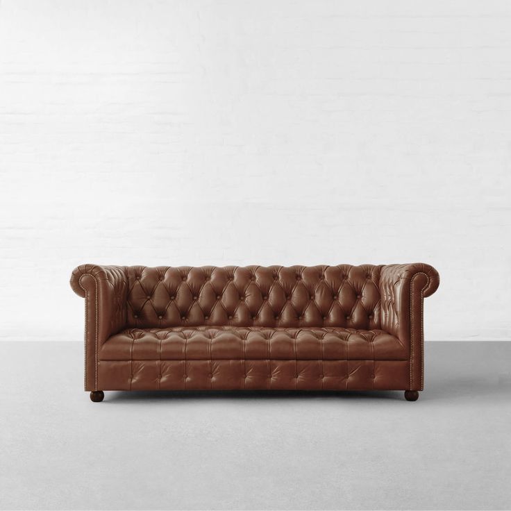 a brown leather couch sitting on top of a white floor