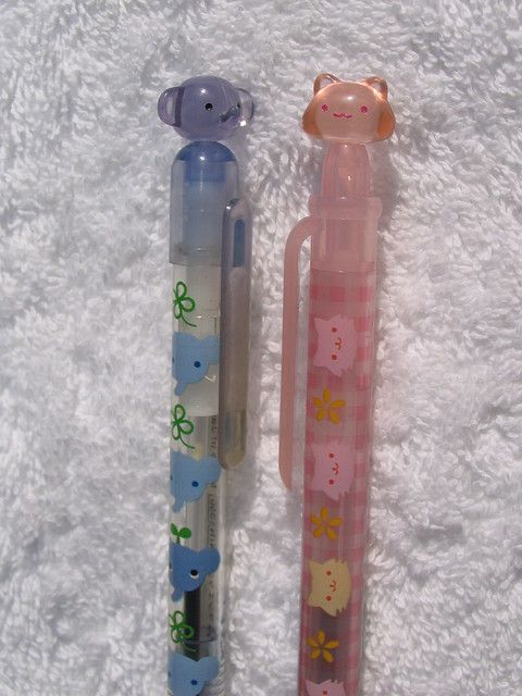 two pens sitting next to each other on top of a white surface with flowers and animals