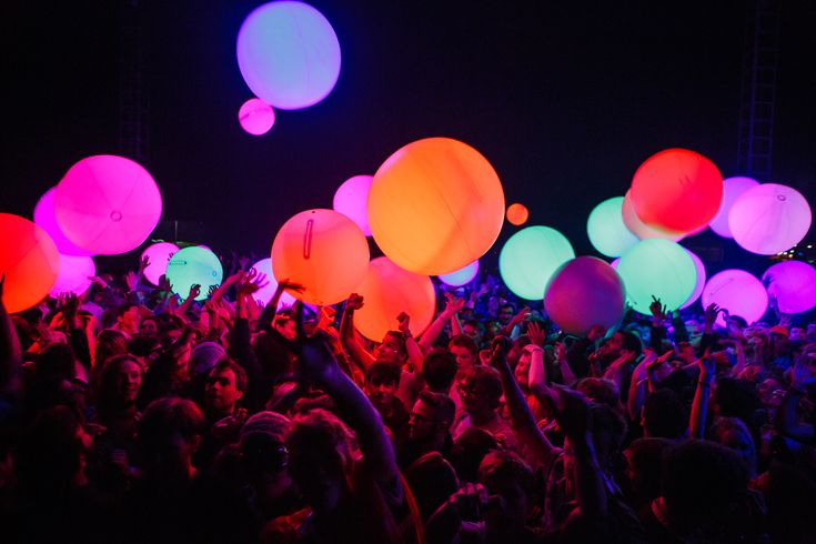 a large group of people at a concert with balloons in the air and onlookers