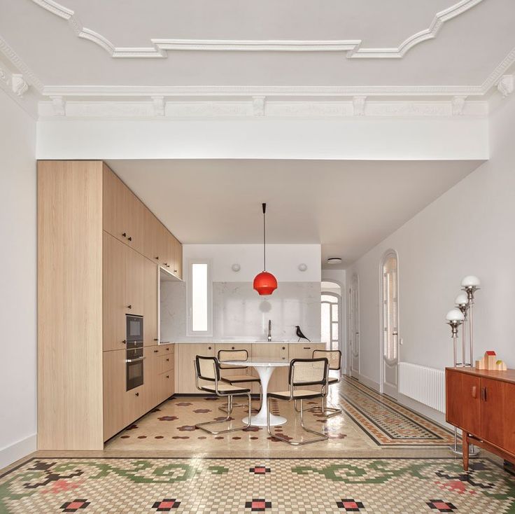 a dining room and kitchen area in an apartment with white walls, wood cabinets, and patterned flooring