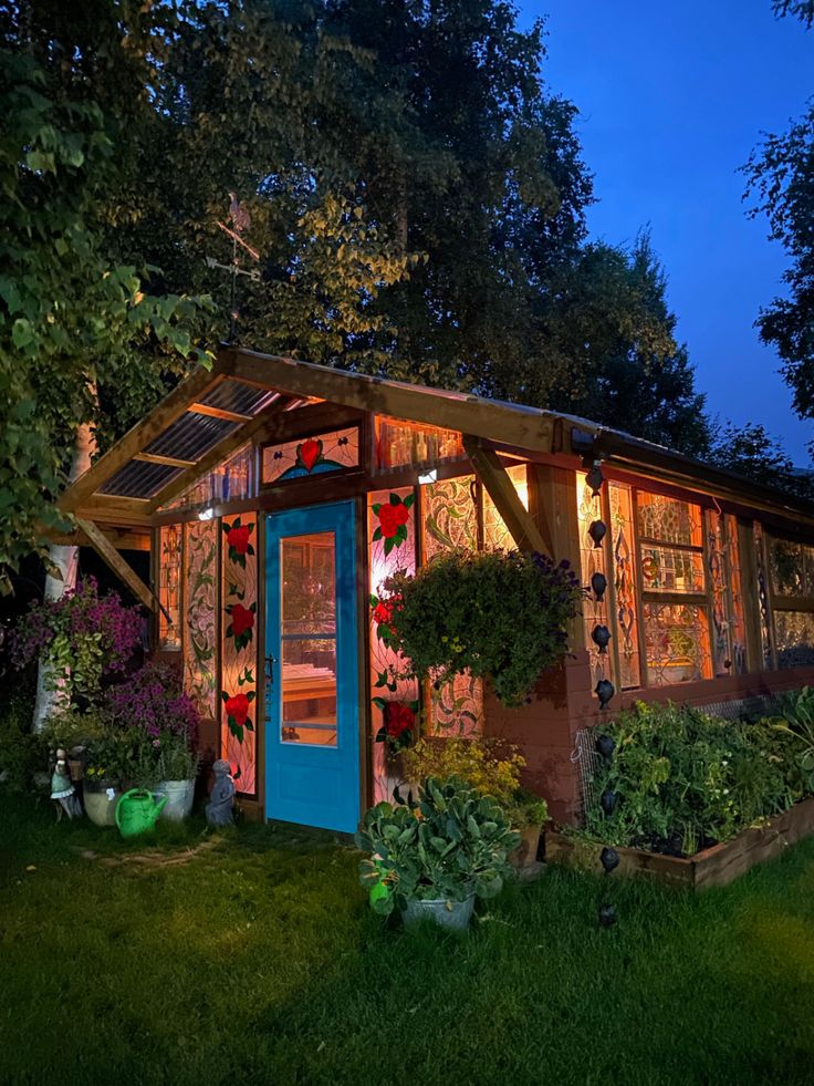 a small shed with plants and lights on it's side in the grass at night