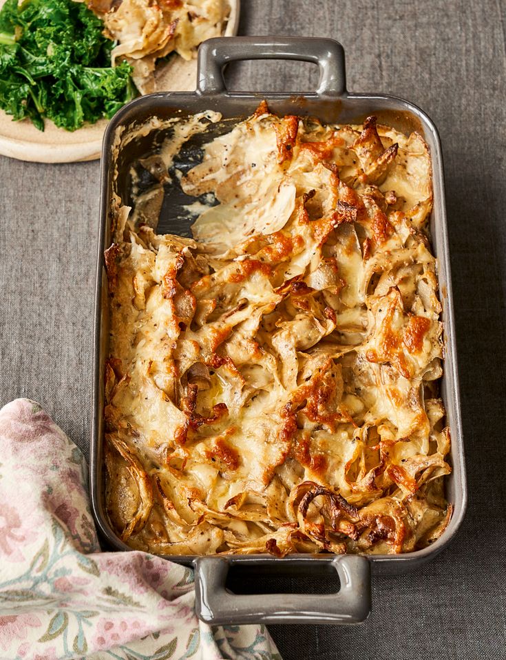 a casserole dish with meat and vegetables in it on a table next to other dishes