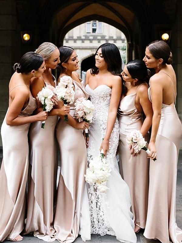 a group of women standing next to each other in long dresses and holding bouquets