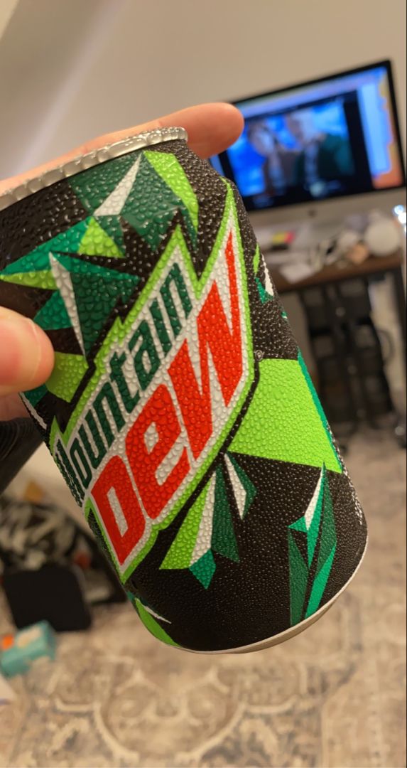 a person holding up a can of mountain dew