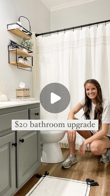 a woman sitting on the floor in front of a bathroom with a white shower curtain