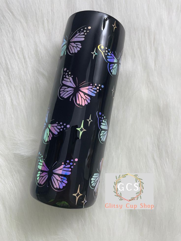 a black tumbler with colorful butterflies on the lid sitting on a white fur surface