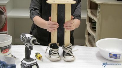 a person standing behind a table with some tools on it and one hand holding a piece of wood