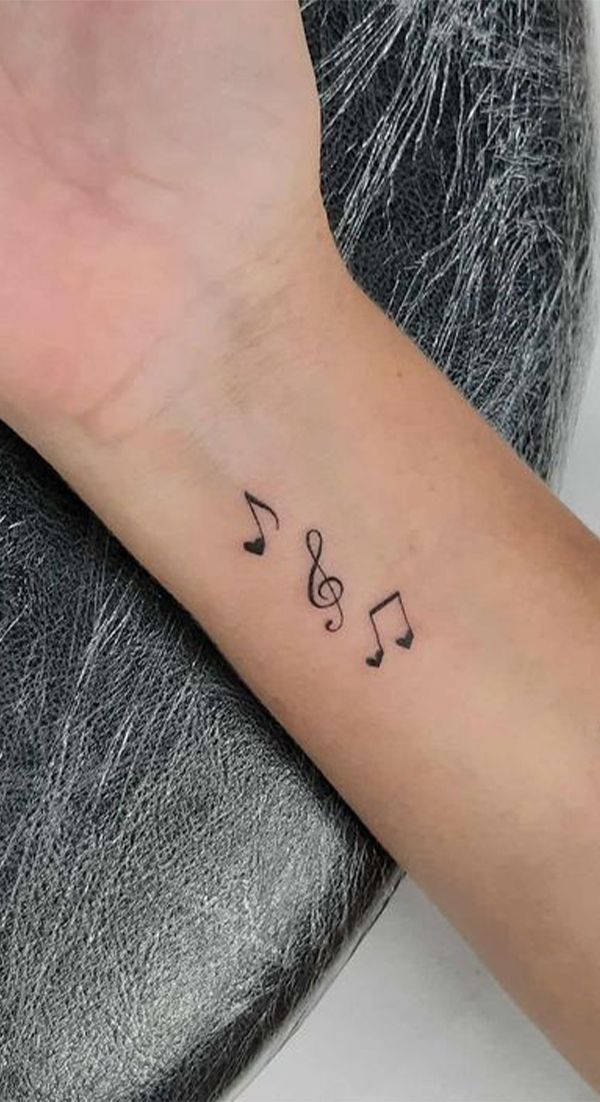 a small wrist tattoo with musical notes on the left side of the arm, and music notes