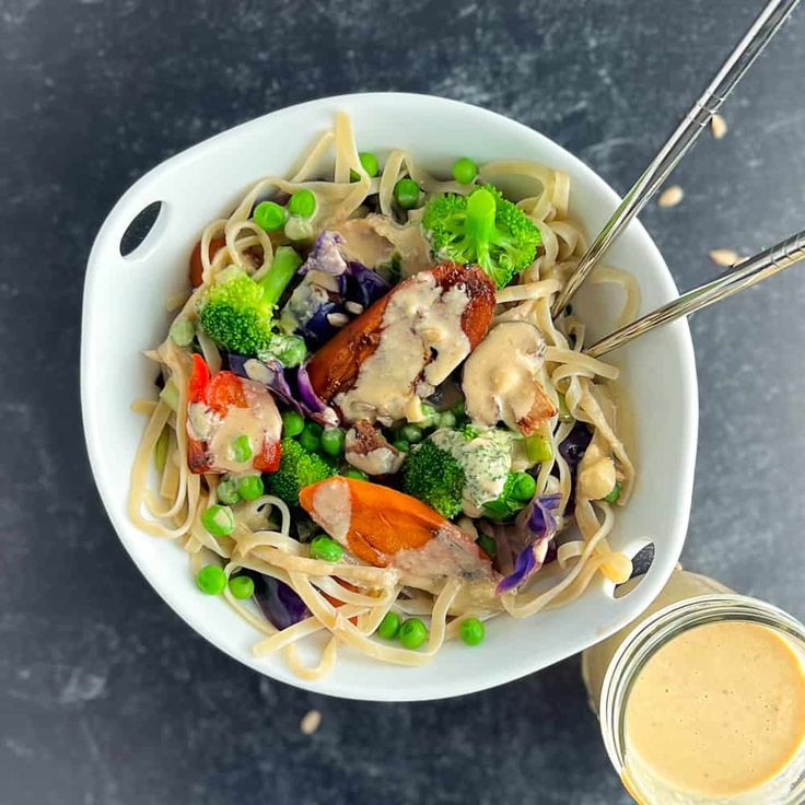 a white bowl filled with noodles and vegetables