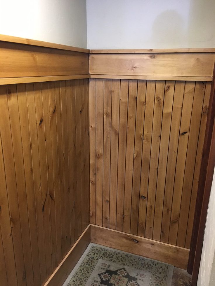 a bathroom with wood paneling on the walls and floor, along with a toilet