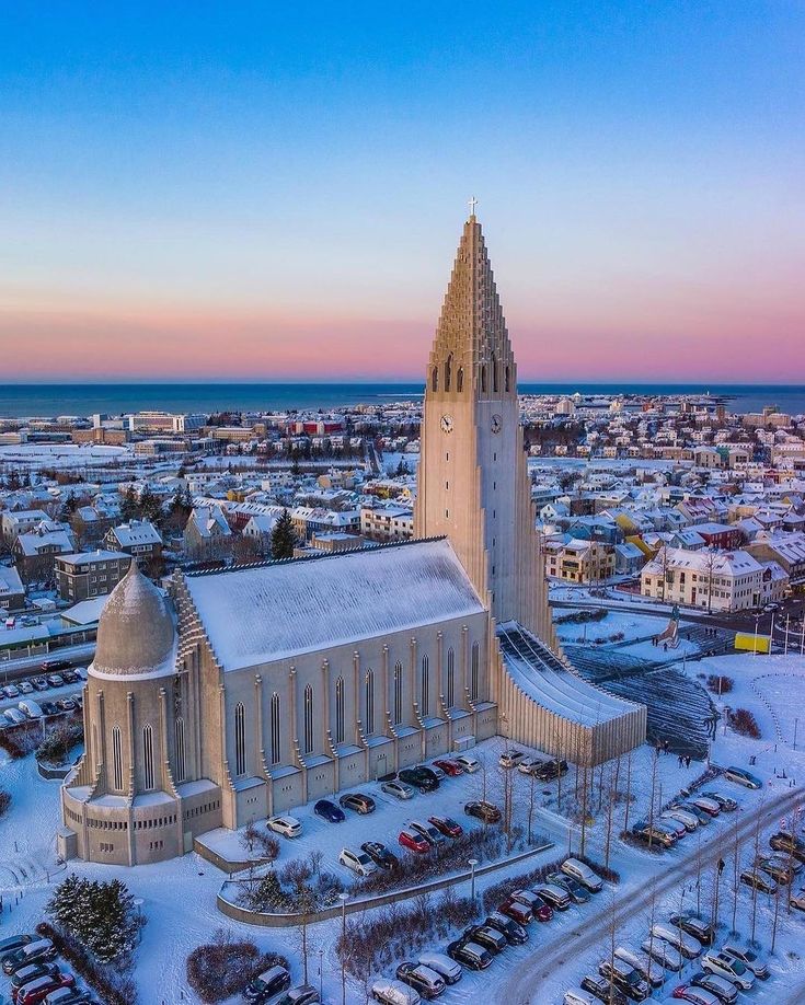 an aerial view of a church and parking lot covered in snow at sunset or dawn